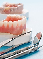 A mouth mold that contains a customized denture and dental instruments lying next to it
