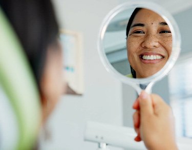 Woman smiling at reflection in dentist office