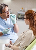 Woman in dental chair talking to dentist