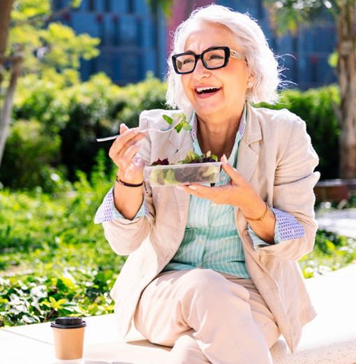 Lady smiles while eating salad