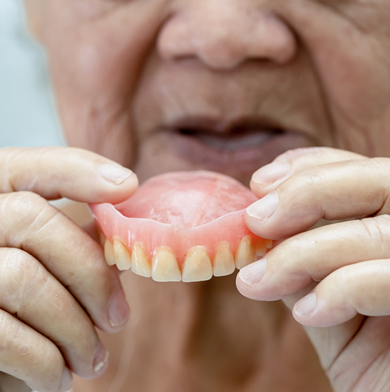Elderly person holding a denture