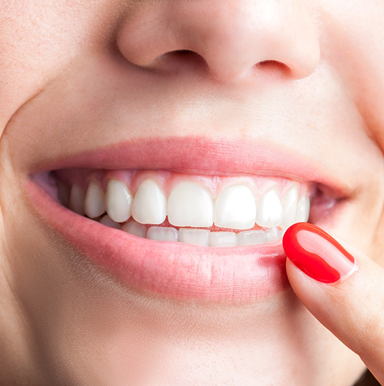 Close up of a smiling person pointing to their teeth