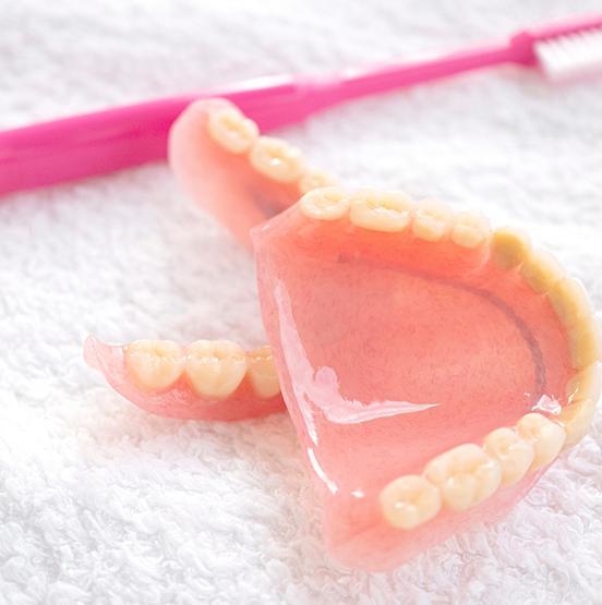 Dentures on a towel next to a toothbrush