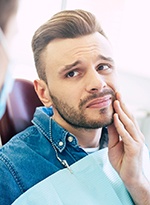 Male patient visiting dentist rubbing jaw in pain