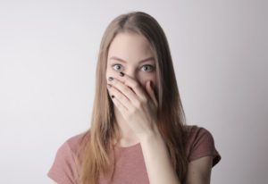 Embarrassed woman covering mouth with hand