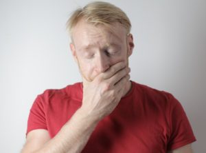 Man with hand over his mouth in pain