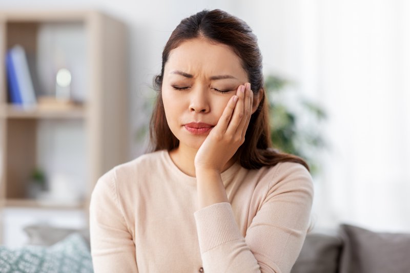 Person holding their cheek in pain