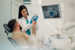 Dentist showing patient a dental implant model.